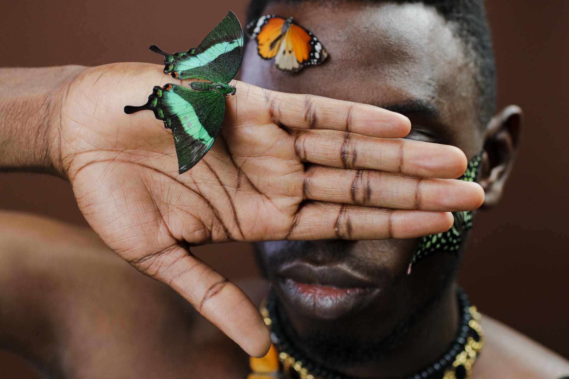 a man covering his face with butterfly on his hand